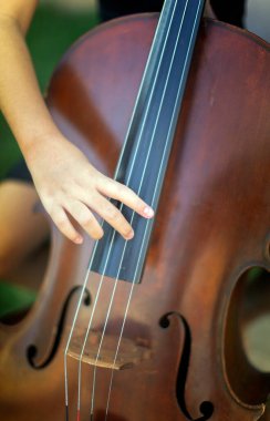 Çocuk parmağını çello teline ve plyingin müzik konseptine yaklaştır.