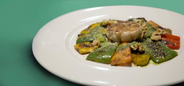 Vejetaryen ızgara manusunu sarımsaklı herb praprika ile servis et, yeşil soslu patates kabağı vejetaryen mezeleri için seramik tabakta.   