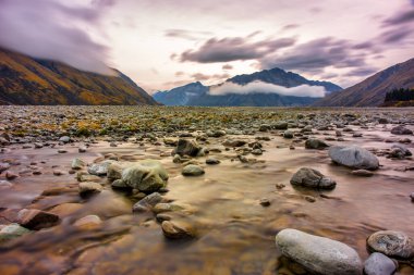 Clyde Nehri 'nin çok kuru nehir yatağı Ashburton yüksek kırsalında, Güney Alpleriyle çevrili.