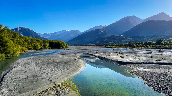 Reflections of the Southern Alps on the crystal clear water of the Rees River near Glenorchy