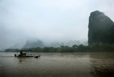 guilin, Çin'li nehirde bir kayıkçı bir geleneksel tekne seyahat.