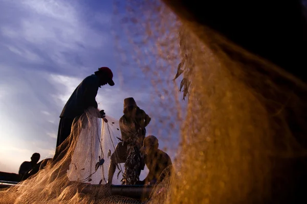 Un pêcheur dans un bateau en mer au coucher du soleil — Photo