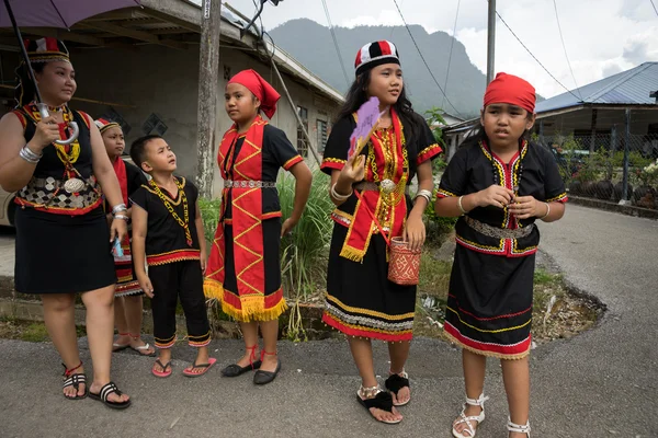 SARAWAK, MALASIA: 1 DE JUNIO DE 2014: Una familia Bidayuh vestida con trajes tradicionales espera que el desfile callejero pase por su casa para celebrar el festival Gawai Dayak . — Foto de Stock