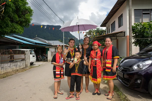 Sarawak, Malaysia: 1. Juni 2014: Eine bidayuh Familie in traditionellen Kostümen wartet darauf, dass die Straßenparade an ihrem Haus vorbeizieht, um das gawai dayak Festival zu feiern. — Stockfoto