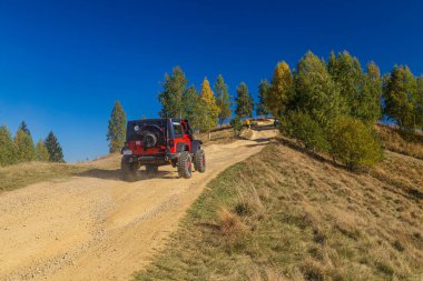 Dağ sonbahar manzarası. Dağ tepelerinin arka planında yürüyüş parkurunda bir SUV. Yaremche köyü, Makovytsia dağının manzarası. Karpatlar. Ukrayna. Turist arazisi