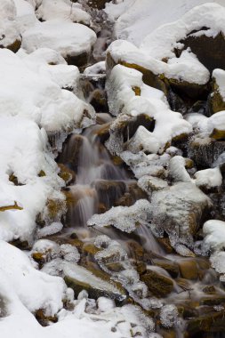 Kışın sonsuz akarsu. Buz ve karla kaplı hızlı dağ nehri. Siyah beyaz fotoğraf