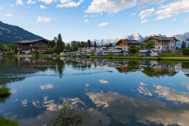 Dağlardaki gölde kamp. Dağlarda aktif yaz uykusu. Dağ zirvelerinin arka planında kamp yapmak. Bulutlar suya yansıyor. Avusturya Alpleri.