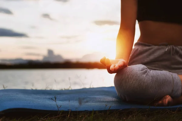 woman doing yoga by the lake in the evening