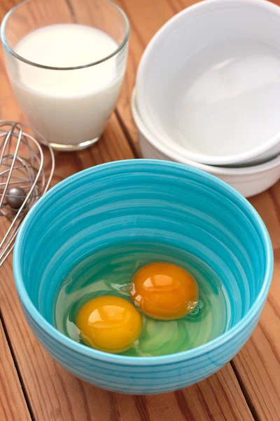 Яйца в голубой миске и стакан молока — стоковое фото