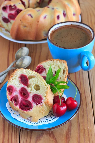 Spons cake met kersen op de blauwe plaat — Stockfoto