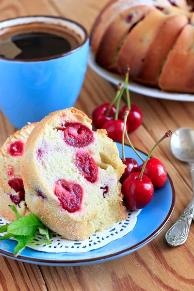 Sponge cake with cherries on the blue plate — Stock Photo, Image