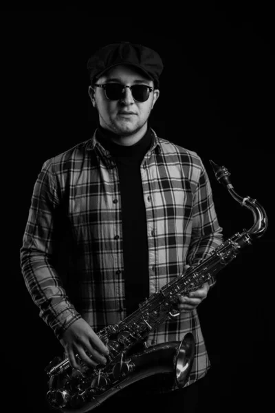 Brutal Sexy Sax Player is Holding a Saxophone. Jazz Saxophonist has Tenor Sax. Black and White. Black Background. Close-up