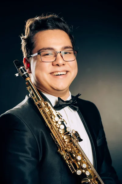 Young Japanese Saxophone Player Posing With Soprano Straight Saxophone.Musician with Brass Musical Instrument. Close-up Portrait. Black Background