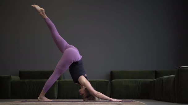 Lonely Woman i Sportswear gör Side Plank i en rymlig yogastudio. Sportig passform Kvinnliga övningar Hatha Yoga. Full längd. Grå bakgrund — Stockvideo