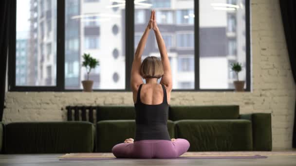 Kvinnan sitter i Lotus Pose och mediterar med öppna händer. Yoga Kvinnlig Träning Yoga Meditation Motion på mattan i hennes vardagsrum hemma. Närbild — Stockvideo