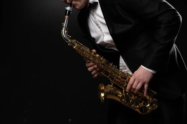 Saxophonist Musician in Black Tuxedo and Bow Tie Plays the Alto Saxophone. Alto Sax Player, Jazz Sazophonist. Black Background. Close-up. Copy Space