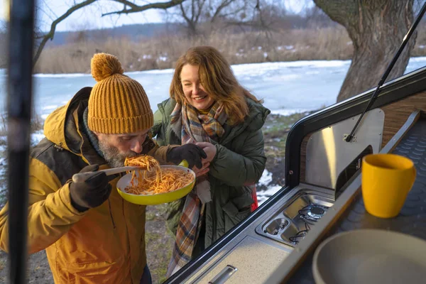饥饿的人在野外用平底锅吃午饭面食 在寒假期间站在小野营后厨房里 家人一起在野外露营 家庭旅行概念 — 图库照片