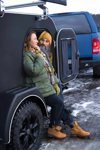 Middle aged couple rest in camper smile good mood at winter vacation in the wild. Traveling across country mature couple rest in camper. woman look with love on her husband. Journey concept.