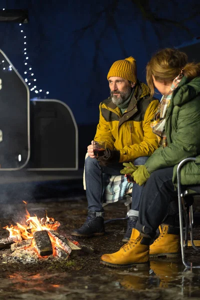 恋爱中的中年夫妇在篝火边热身 在冬天坐在格子布的毛毯上喝茶 中年夫妇坐在雪中篝火边 家庭假期和旅行概念 — 图库照片