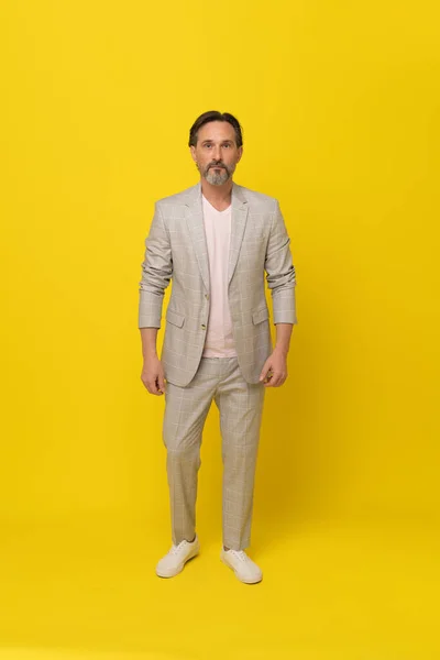 Handsome businessman in white suit. Middle aged business man in white, grey casual suit folded arms smiling looking at camera isolated on yellow background. Business concept.