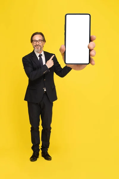 Wskazując Smartfona Białym Ekranem Podekscytowany Biznesmen Średnim Wieku Patrząc Aparat — Zdjęcie stockowe