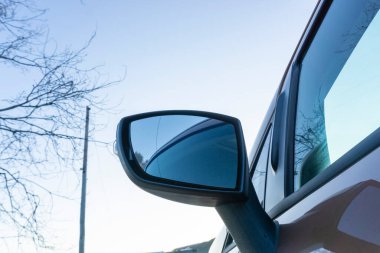 Arka planda gökyüzü olan araba dikiz aynası