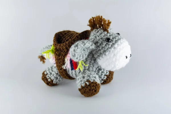 Lead-colored donkey with its saddlebag. Crochet stuffed animal