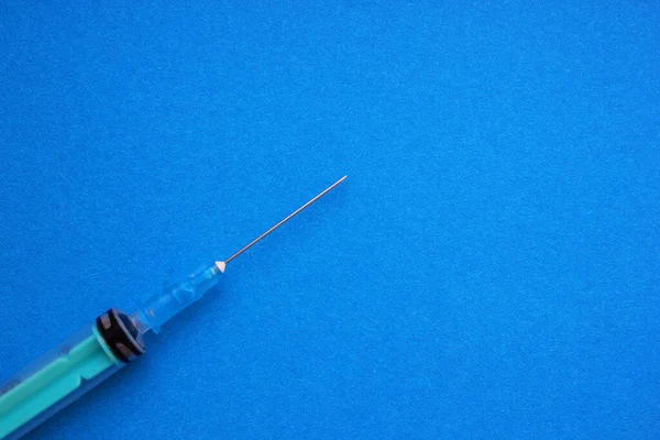 Eine Spritze mit Nadel ruht auf blauem Grund. Impfung, Injektion, Injektion, Behandlung, Antibiotikum, nakrotisch. Das Konzept der Medizin und Immunität. Flach. Kopierraum — Stockfoto