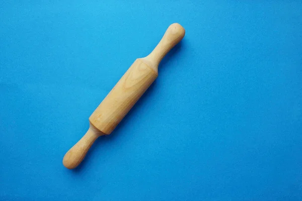 Mavi zemin üzerinde ahşaptan yapılmış bir test için bir taş. Pişirme ve pişirme. Aşçılık. Yukarıdan bak. Uzayı kopyala Testin sonucu solda ezilmiş..