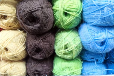 Dükkan camında çok renkli yün iplik deseni var. Örgü örmek için arka plan. El yapımı kış giysileri için iplik örüyorum. İplik yumağıyla renkli arkaplan.