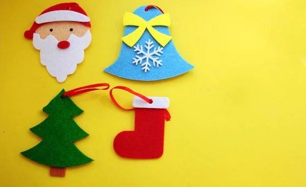 Рождественские елки игрушки на желтом фоне. Санта Клаус, Белл, ель, носок. Вид сверху. Рождество и Новый год. Игрушки на елке. Детство. Пофельные игрушки. Копирование пространства — стоковое фото