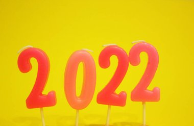 2022 numaraları sarı arka planda. Pembe Noel mumları 2022. Mumlar sayılar şeklinde. Yalıtılmış. Yeni yıl. Noel zamanı. Boşluğu kopyala