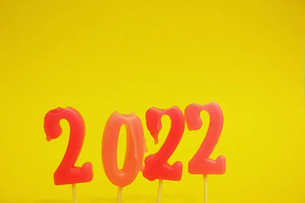 Числа 2022 находятся на жёлтом фоне. Розовые рождественские свечи 2022 года. Свечи в виде чисел. Изолирована. Новый год. Рождество. Копирование пространства — стоковое фото