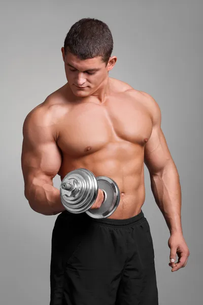 Handsome muscular man working out with dumbbells on grey background — Stock Photo, Image