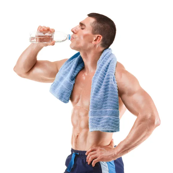 Young muscular man with blue towel over neck, drinking water, isolated on white background — Stock Photo, Image