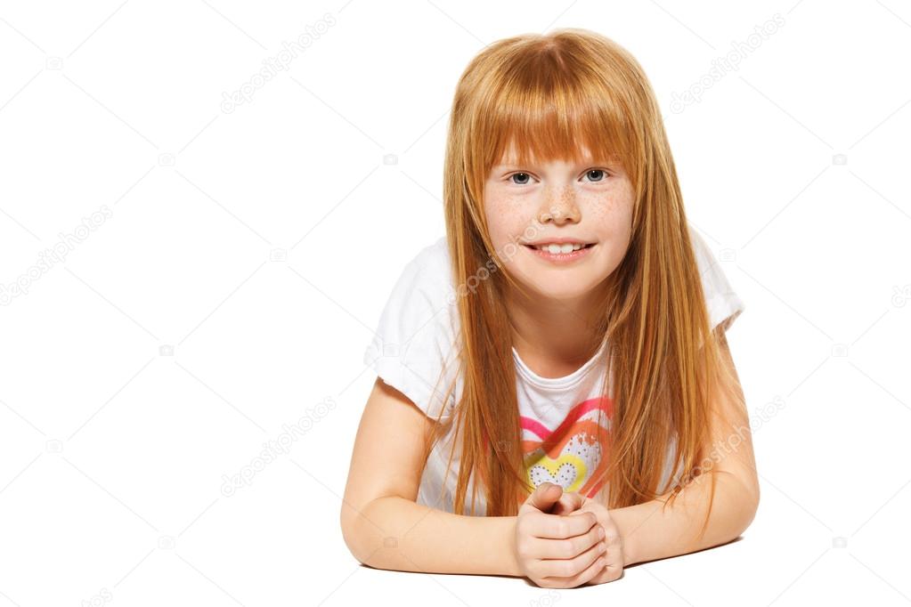 A cheerful little girl with red hair is lying. isolated on the white background
