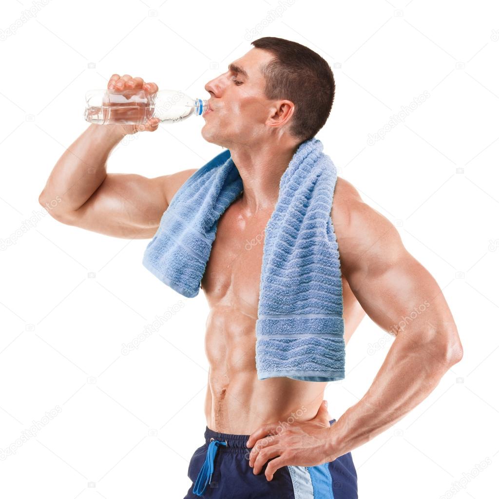 Young muscular man with blue towel over neck, drinking water, isolated on white background