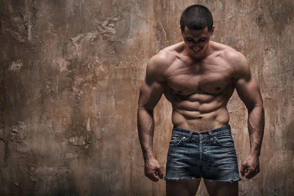 Muskulöser Mann auf Wandhintergrund — Stockfoto