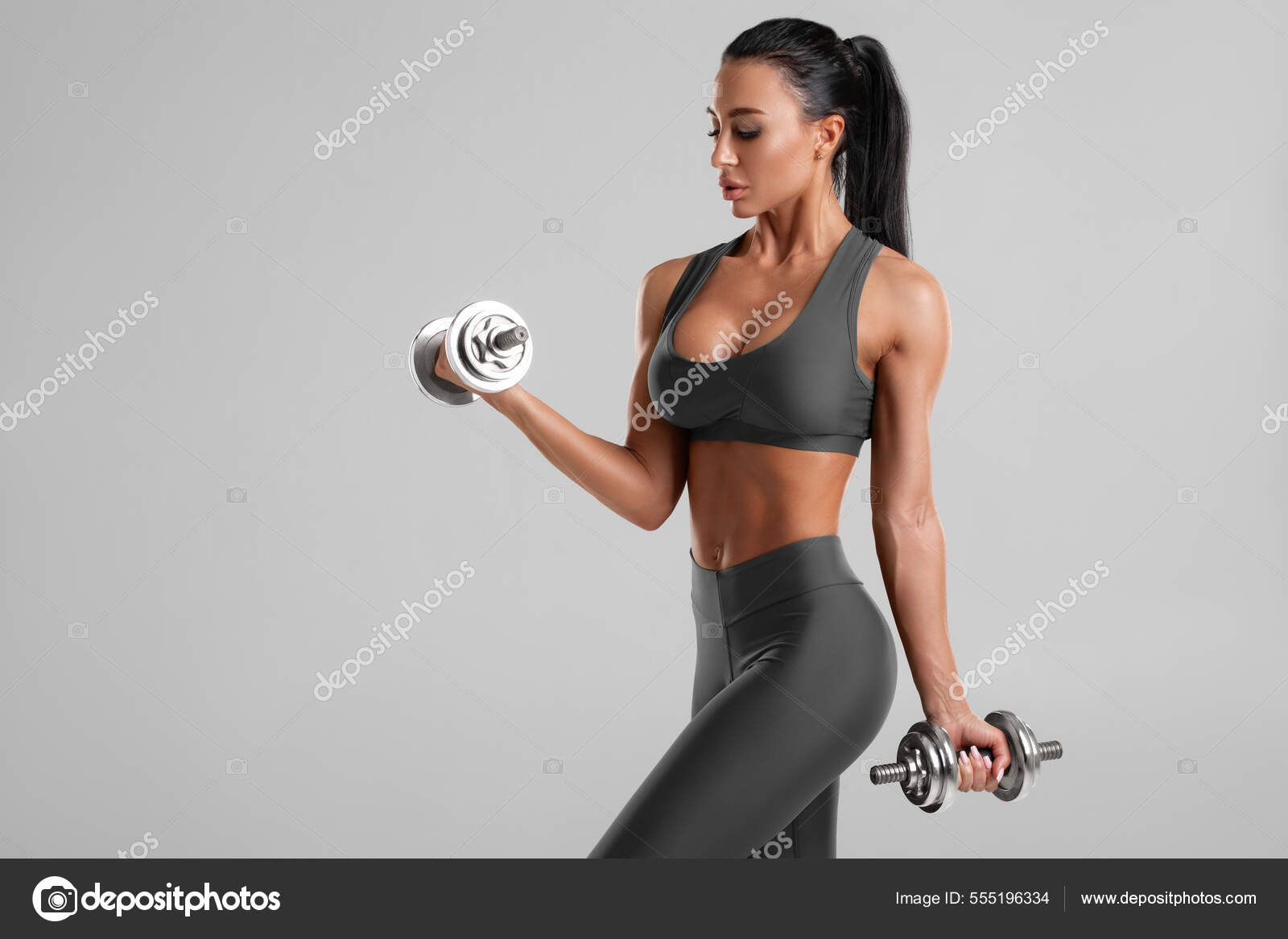 ダンベルを持つ美しいフィットネス女性 灰色の背景の上にアスレチックガール ストック写真 C Nikolas Jkd