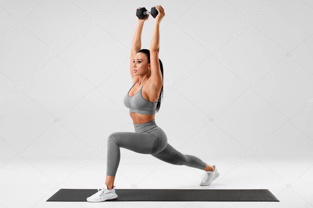 Athletic girl doing lunges exercises with dumbbell, leg muscle training. Fitness woman doing front forward one leg step lunge