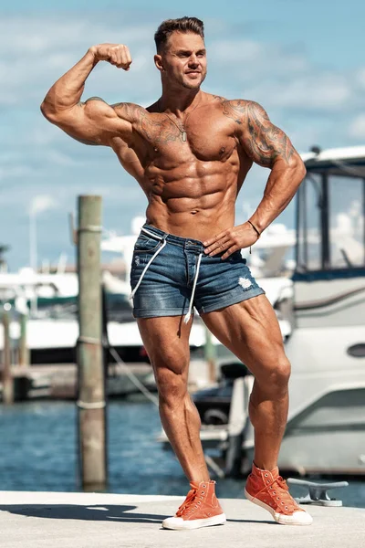 Muscular man showing muscles outdoors. Strong male naked torso abs