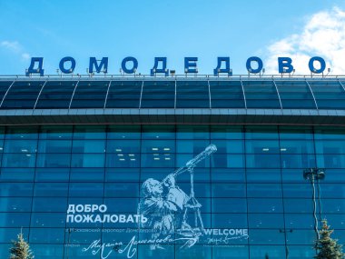 Moskova, Rusya - 5 Ekim 2021: Moskova Domodedovo Havaalanı. Binanın çatısındaki havaalanının ismi mavi gökyüzü ve bulutların arka planına karşı. Yakın plan..