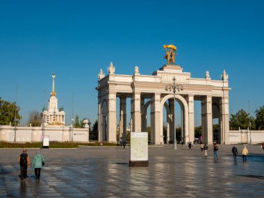 Moskova, Rusya - 5 Ekim 2021: VDNKh 'nin ana girişinin kemeri. İnsanlar parkın girişine yakın meydanda yürüyorlar..