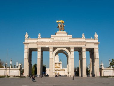 Moskova, Rusya - 5 Ekim 2021: VDNKh 'nin ana girişinin kemeri. İnsanlar güneşli bir sonbahar gününde parkın girişindeki meydanda yürürler..
