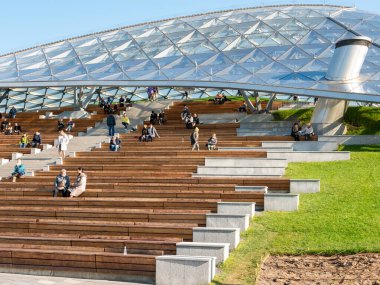 Moskova, Rusya - 5 Ekim 2021 Zaryadye Parkı. İnsanlar güneşli bir sonbahar gününde Zaryadye konser salonunun büyük cam kubbesi altında dinleniyorlar..