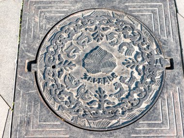 Zaryadye Parkı. Kapak bir süs, bir yaprak resmi ve ortasında Zaryadye yazısıyla kaplanmış. Yakın plan..