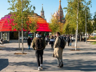 Moskova, Rusya - 5 Ekim 2021 Zaryadye Parkı. İnsanlar Kızıl Meydan ve Aziz 'in arka planında parlak bilgi merkezine yakın yürüyorlar. Güneşli bir sonbahar gününde Basil Katedrali.
