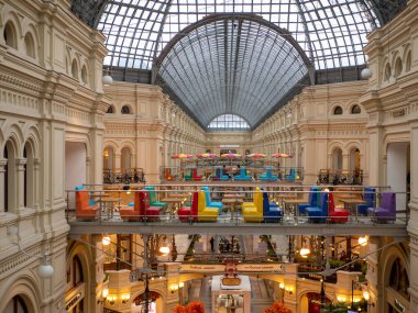 Moskova, Rusya - 5 Ekim 2021: GUM ana mağaza. En üst katta, çatının kubbesinin altında parlak renkli kanepeleri ve şemsiyeleri olan kafeler var..