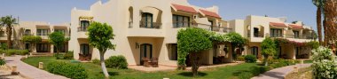 Hurghada, Mısır- 22 Eylül 2021: iki katlı evleri olan otelin yeşil alanının panoramik manzarası.