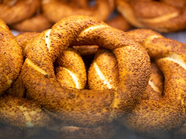Simit - turkish bagels covered with sesame seeds are on the shop window behind the glass. Close-up.